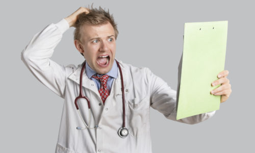 Male doctor terrified looking at medical reports over gray background